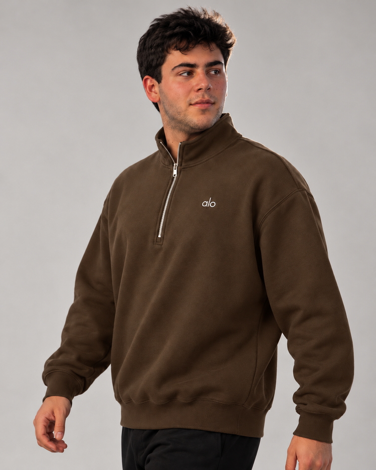 Modelo caminando con sudadera ALO Accolade 1/4 Zip café, vista de tres cuartos